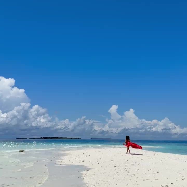 Run on a sandbank in Maldives in a red dress