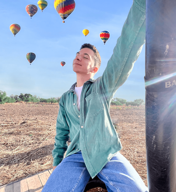 Man posing with hot air balloons in the background